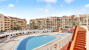 Un complexe hôtelier doté d’une grande piscine, de nombreux balcons et offrant une vue sur un ciel dégagé.