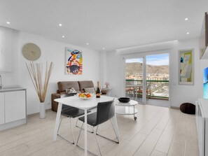 Enjoy a mountain view from the large window in this stylish living space with a dining area, sofa, and kitchen.
