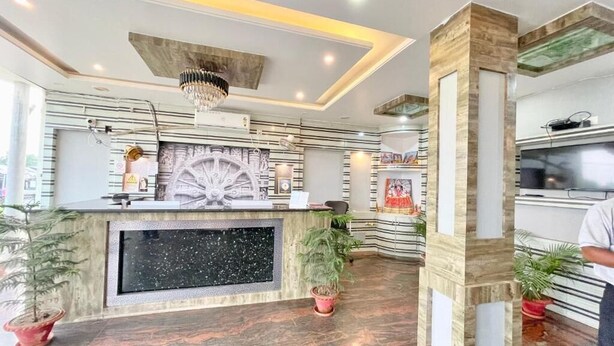 A reception area with a marble counter, a chandelier, and potted plants. - Hotel Trends - near Sea Beach & Temple (Puri)