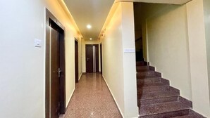 A hallway with a carpeted floor, a staircase, and a door at the end. - Hotel Trends - near Sea Beach & Temple (Puri)