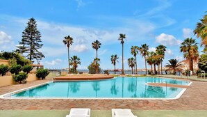 A swimming pool with two white sun loungers in the foreground, surrounded by palm trees and a clear sky. - Casa Marinita, Penthouse By The Sea (Arona)