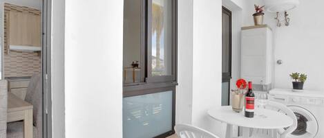A compact living space with a dining area, a washing machine, and a window with a view.