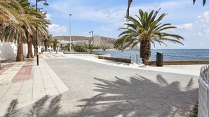 A coastal promenade with palm trees, a clear sky, and a view of the sea. - Ferdy's Home, Pool, Wi Fi, Downtown Los Cristianos (Los Cristianos)