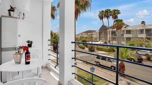 A balcony with a white table, potted plants, and a bottle of wine. - Ferdy's Home, Pool, Wi Fi, Downtown Los Cristianos (Los Cristianos)