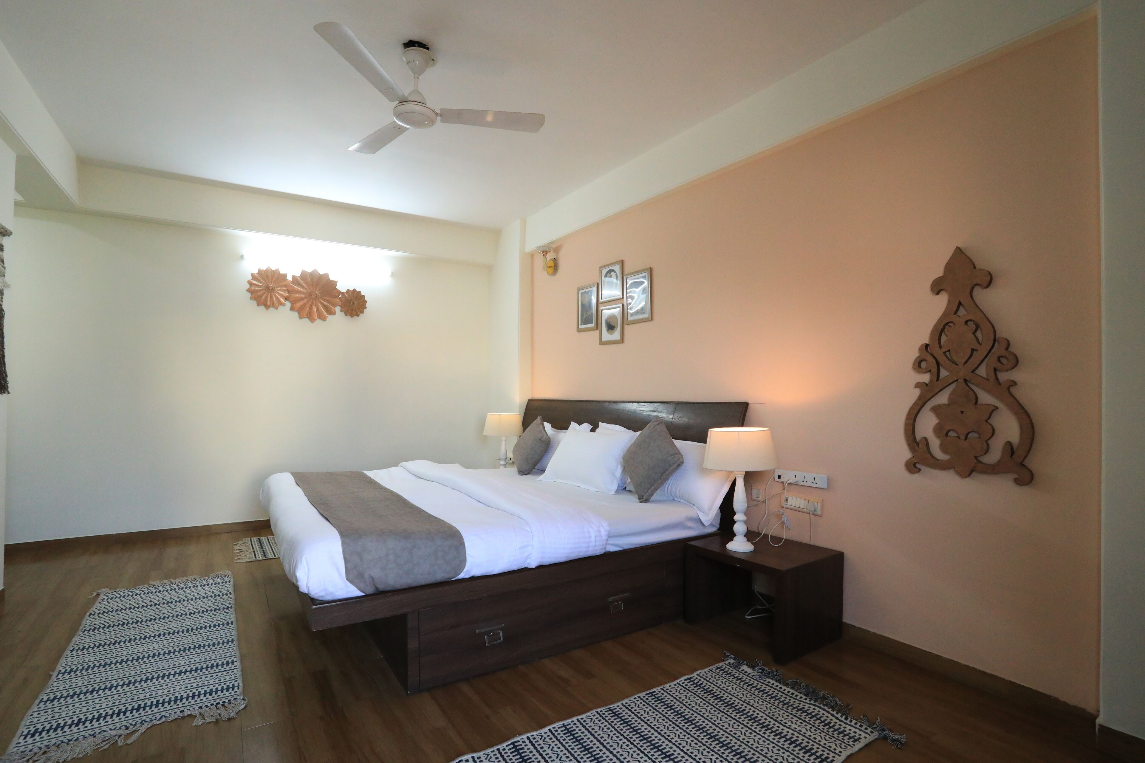 A bedroom with a bed, nightstands, a ceiling fan, and decorative wall art.