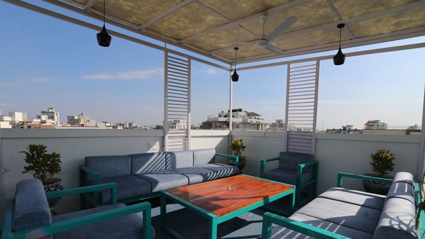 A rooftop terrace with outdoor seating, a wooden table, and potted plants. - Banipark Service Apartment (Jaipur)