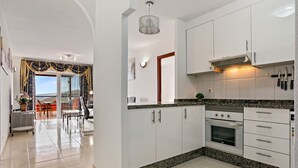 Cozinha moderna com armários brancos, forno embutido e bancada de granito.