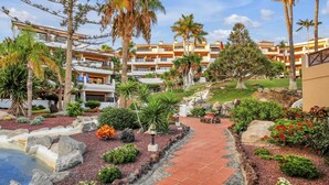 A resort with multiple-story buildings, a landscaped garden with a pathway, and palm trees.