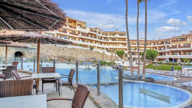 A resort with a pool area, outdoor seating, and a building with multiple balconies.