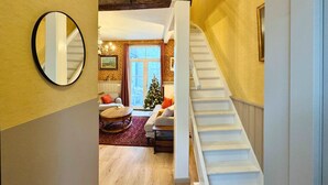 Een trap die leidt naar een woonkamer met een kerstboom, een ronde spiegel en een bank.