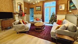 Een gezellige woonkamer met twee banken, een salontafel, een televisie en een kerstboom.