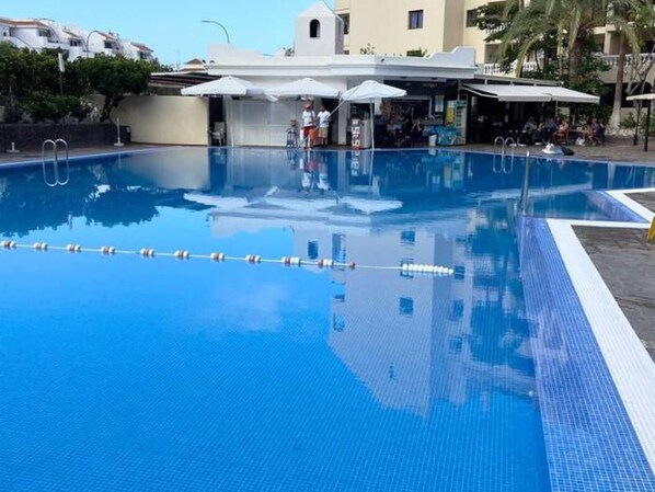 A swimming pool with clear blue water, a diving board, and a lifeguard stand.