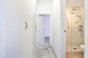 A modern bathroom with a glass shower enclosure, a toilet, and a marble-tiled floor.