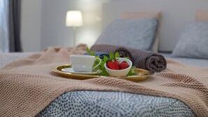 A neatly made bed with a white cup, a bowl of strawberries, and a rolled towel on a tray. - The Stone Apartment, Los Gigantes, Heated Pool (Acantilados de Los Gigantes)