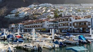 A coastal town with a marina filled with boats, white buildings with balconies, and a hillside in the background. - The Stone Apartment, Los Gigantes, Heated Pool (Acantilados de Los Gigantes)