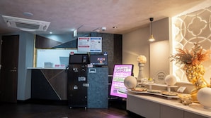 A reception area with a counter, a digital sign, and a decorative vase. - MANORHOUSE - Adult Only (Warabi)