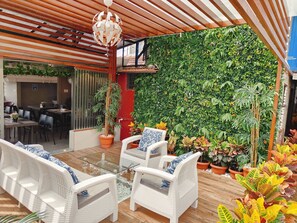 Enjoy al fresco dining under a shaded pergola surrounded by lush greenery and comfortable seating.