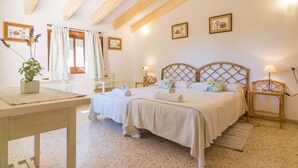 A bedroom with two beds, wooden beams, a window with curtains, bedside lamps, and framed pictures on the wall. - Can Ferrer - Villa With Private Pool In Pollença (Pollen Ça, Illes Balears)