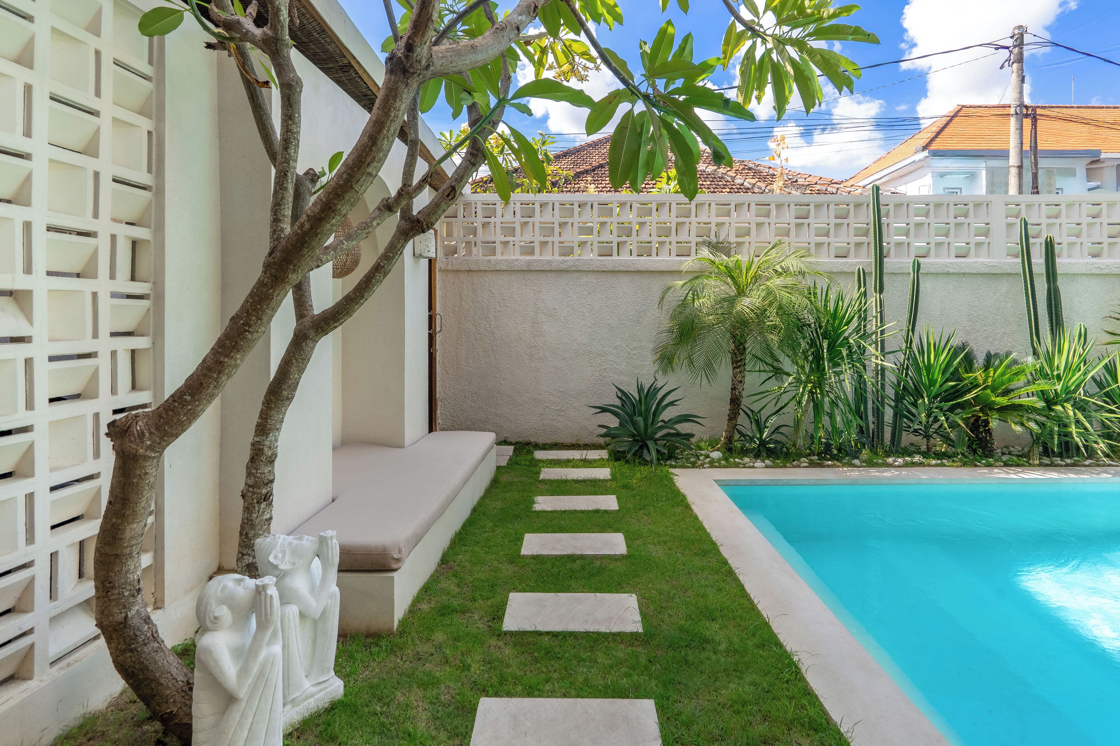 A swimming pool with a stone pathway leading to a white fence.