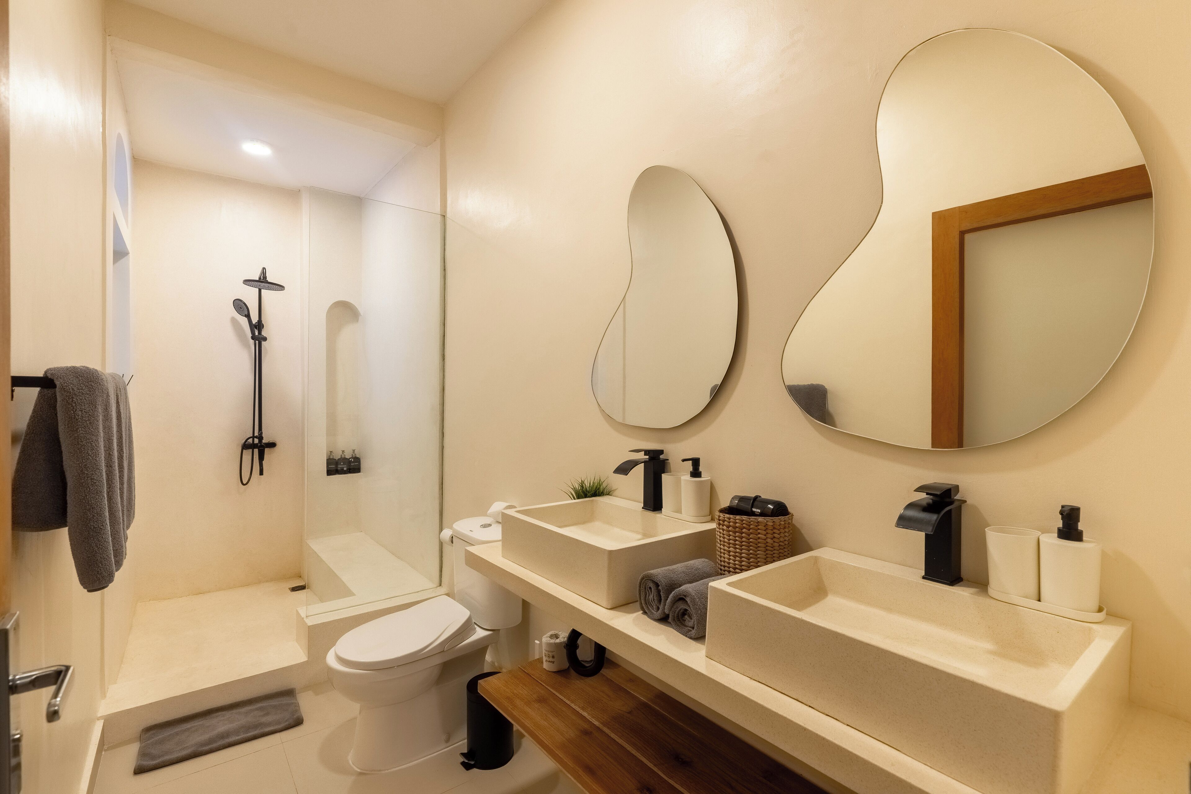 Un baño moderno con ducha, inodoro y dos lavamanos.