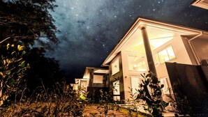 A modern house with a starry night sky visible through the open windows. - CORAL ISLAND (Nago)