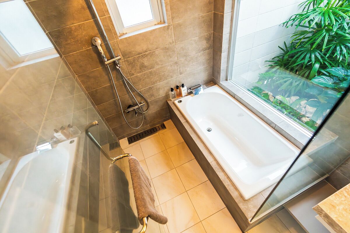 Une salle de bain moderne avec une douche à parois de verre, une baignoire et une petite fenêtre.