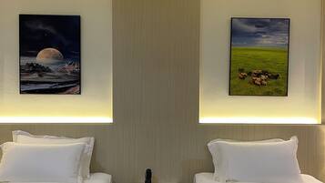 Una habitación de hotel con dos camas, una mesita de noche y dos cuadros colgados en la pared.