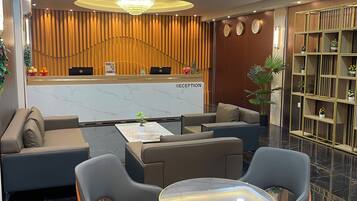 Una moderna zona de recepción con un mostrador de mármol, asientos cómodos y una planta decorativa.
