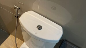 Een modern toilet met een zuigdouche, een witte zitting en een bedieningspaneel aan de muur.