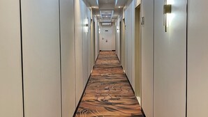 Een hotelgang met een lange, beklede vloer en een rij deuren aan beide zijden.