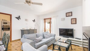 Un soggiorno con divano, televisore e zona pranzo con sedie.