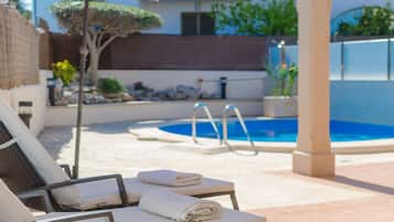 Ein Poolbereich mit Liegestühlen und einer Pergola.