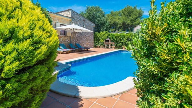 A swimming pool with lounge chairs and a stone building in the background.