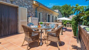An outdoor patio with wicker furniture, a stone building, and a view of the surrounding area.