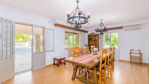 A dining area with a wooden table and chairs, a chandelier, and a view of the outdoors.