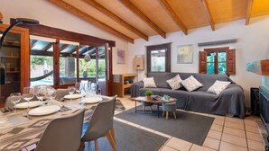 A dining area with a table set for four, a sofa, and a small side table with a plant. - Ca Na Rosa - Villa With Private Pool In Campanet (Campanet, Illes Balears)