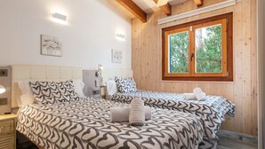 A bedroom with two beds, wooden walls, a window with a view, and a bedside table with a lamp. - Ca Na Rosa - Villa With Private Pool In Campanet (Campanet, Illes Balears)