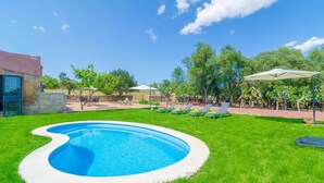 A swimming pool surrounded by a grassy lawn, with lounge chairs and umbrellas in the background. - Can Potdir - Villa With Private Pool In Ariany (Ariany, Illes Balears)