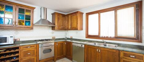 A kitchen with wooden cabinets, a stainless steel sink, a built-in oven, and a dishwasher.