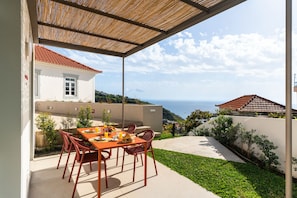 Enjoy a serene dining experience with a view of the sea from this outdoor space.