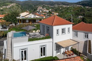 A modern house with a rooftop pool, a covered patio, and a view of a hillside village. - Beautiful villa with rooftop pool | CarmHim (Calheta)