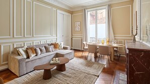 A spacious living room with a sofa, coffee table, and dining area. - Magnificent Apartment Etoile Hoche Saint Honore (Paris)