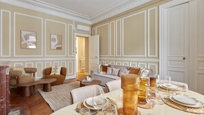 A well-appointed room with a dining area set for a meal, a sofa, and a coffee table. - Magnificent Apartment Etoile Hoche Saint Honore (Paris)