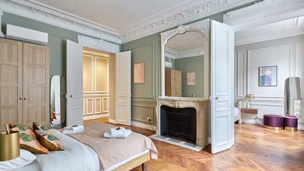 A spacious bedroom with a large bed, a fireplace, and a mirror. - Magnificent Apartment Etoile Hoche Saint Honore (Paris)