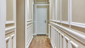 A hallway with a wooden floor, white walls, and a white door at the end. - Magnificent Apartment Etoile Hoche Saint Honore (Paris)