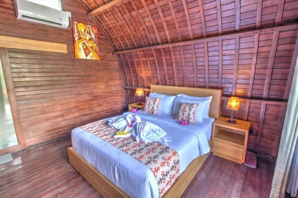 Una stanza in legno con un letto, comodini e un condizionatore d'aria a muro.