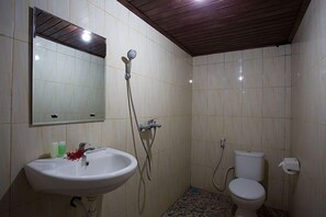 Et badeværelse med vask, spejl, bruser, toilet og flisegulv.