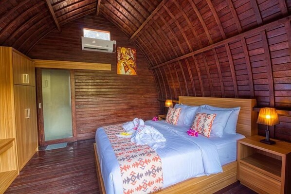 Una habitación de madera con una cama, una mesita de noche y una puerta.