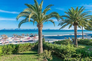 Una playa con palmeras, tumbonas y sombrillas.