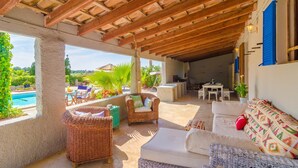 Un espace extérieur abrité, aménagé avec des meubles en osier, une piscine et un coin repas.